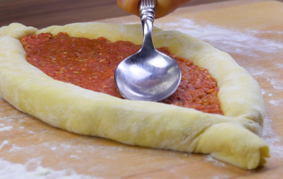 Das Schiffchen wird in der Mitte mit Hackfleisch mit TomatensoÃŸe bestrichen