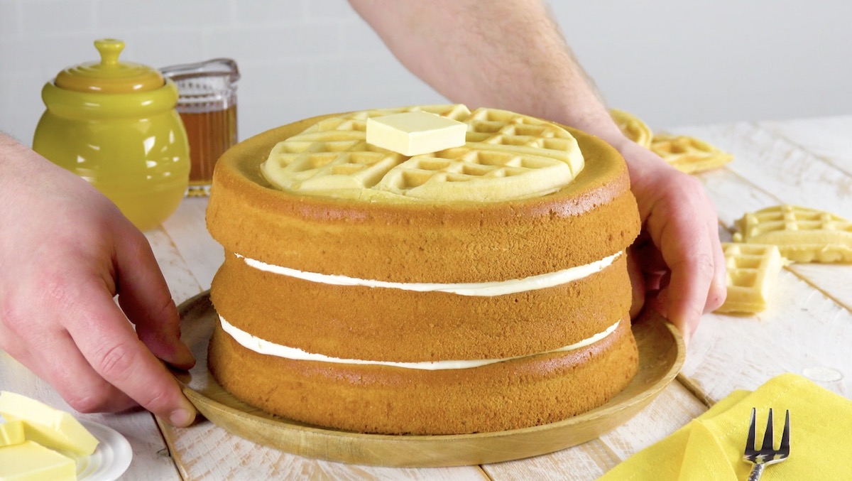 Waffelkuchen mit cremiger FÃ¼llung und einem StÃ¼ck Butter obendrauf wird auf Tisch gestellt