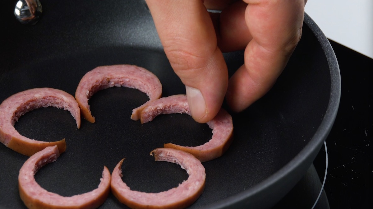 Die ausgestantzten Wurstscheiben werden in Pfanne zu Blume gelegt