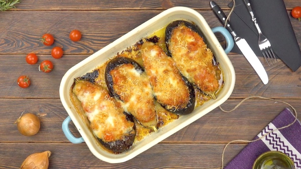 Aubergine al forno mit Mozzarella, 4 Auberginen in der Auflaufform, mit Käse überbacken, Draufsicht.