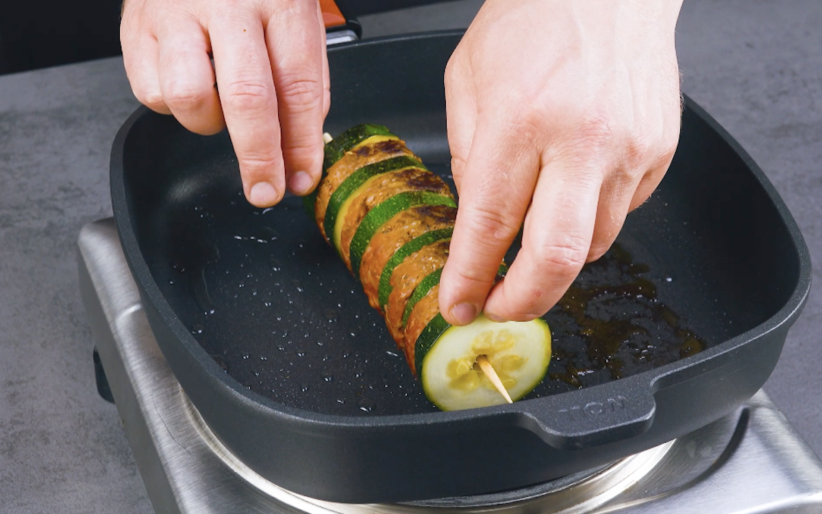 Ein Zucchini-Hackfleisch-SpieÃŸ wird in Pfanne angebraten