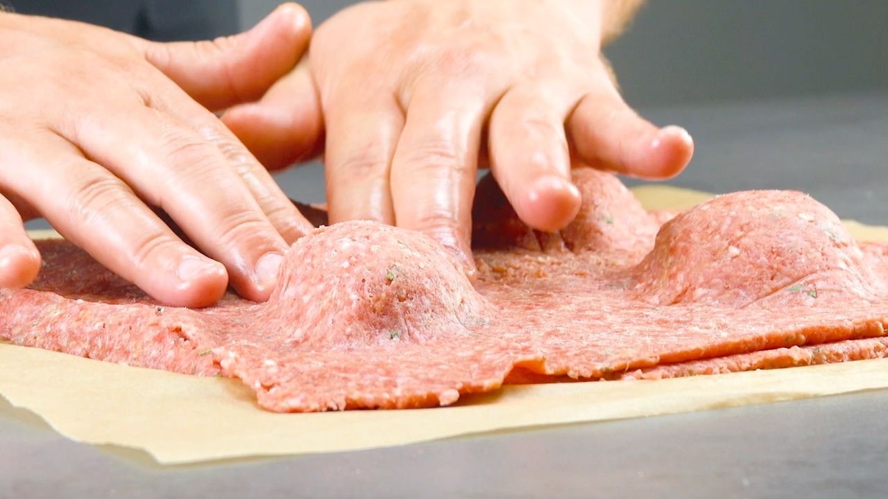 Hackfleisch wird um KÃ¤sefÃ¼llung mit HÃ¤nden festgedrÃ¼ckt