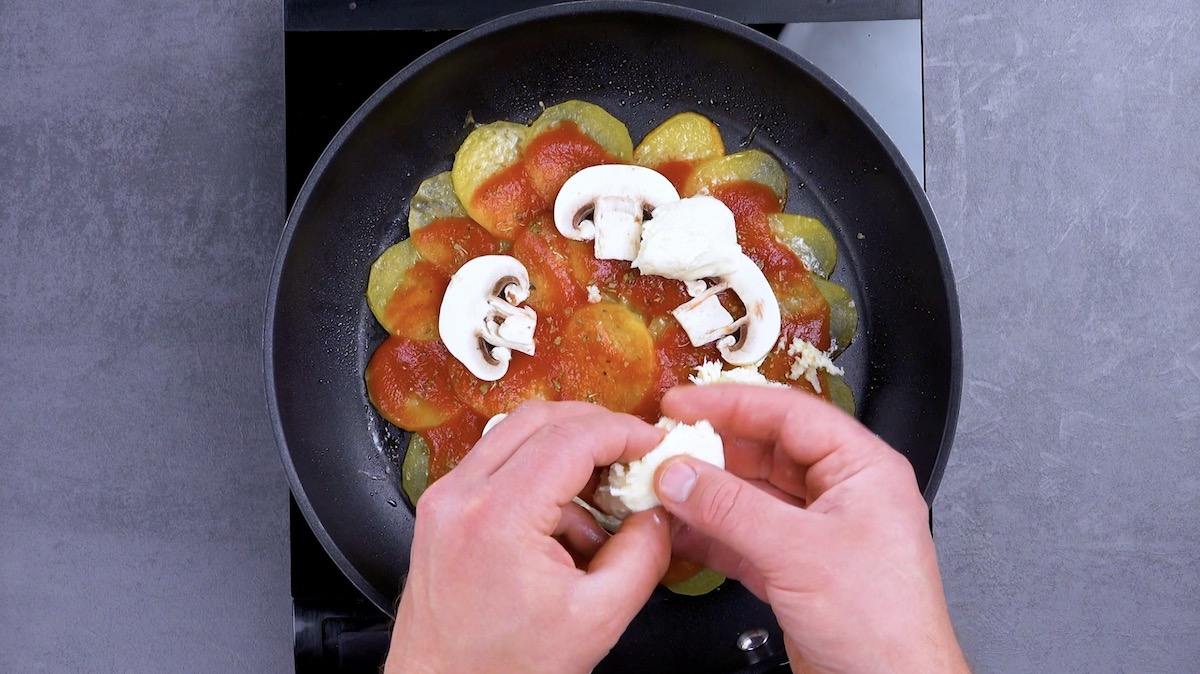 MozzarellastÃ¼cke werden auf Pizza mit Kartoffeln in Pfanne platziert