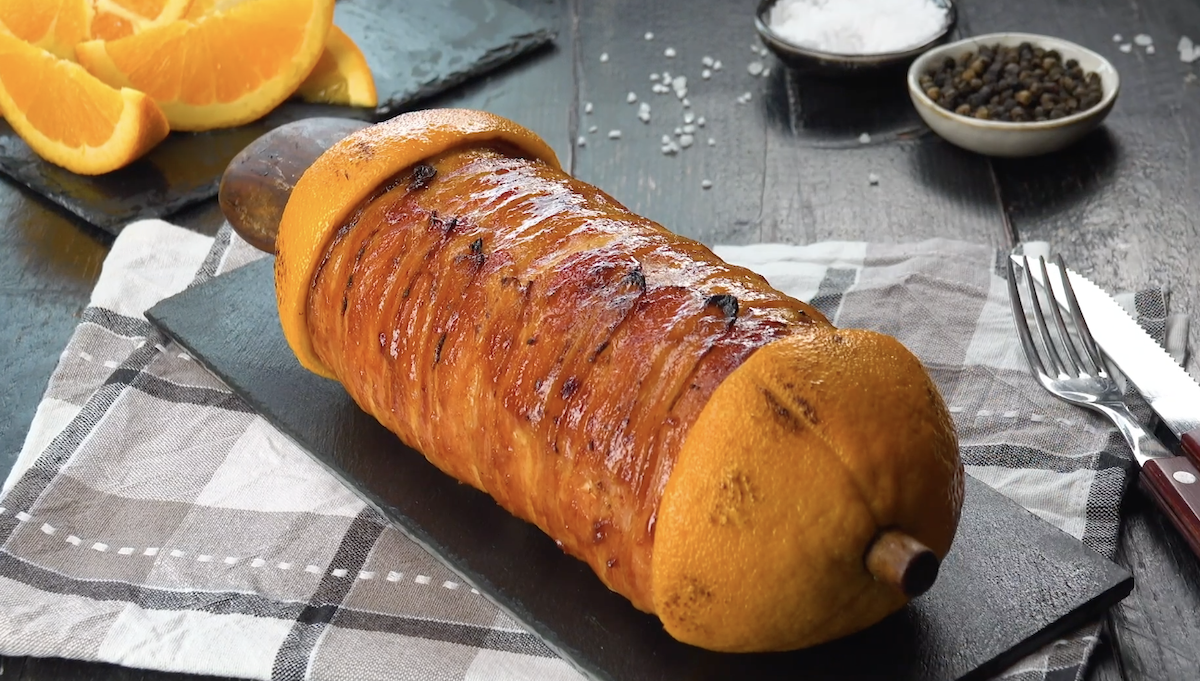 Ein Cordon bleu am Spieß vom Grill auf einer Schieferplatte.