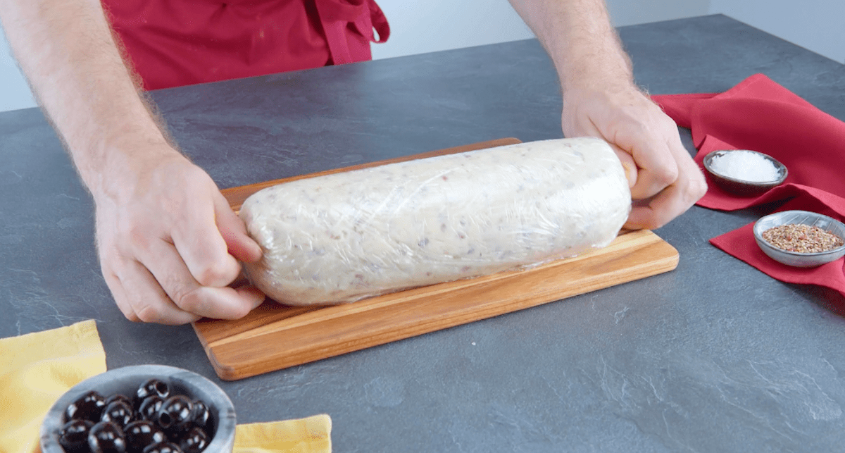 Eine rohe HÃ¤hnchen Croqueta wird in Frischhaltefolie gerollt