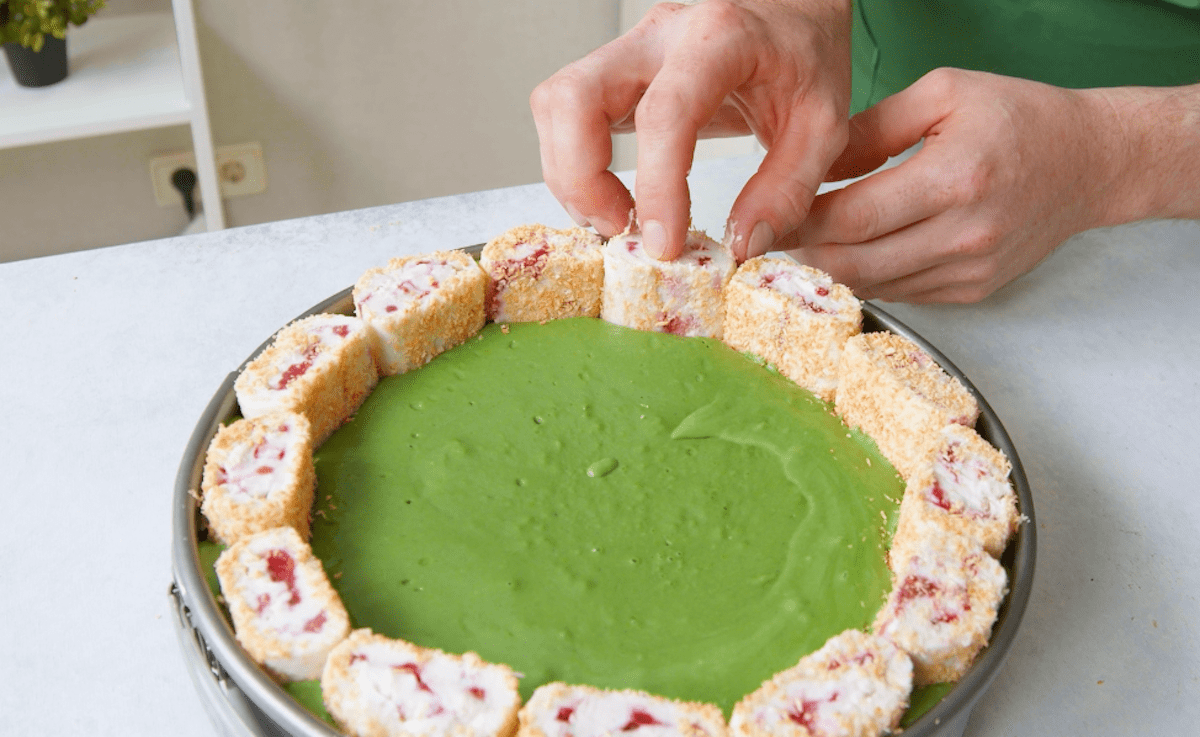 Die Kokospudding-RÃ¶llchen werden hochkant in die Matcha FrischkÃ¤secreme gedrÃ¼ckt