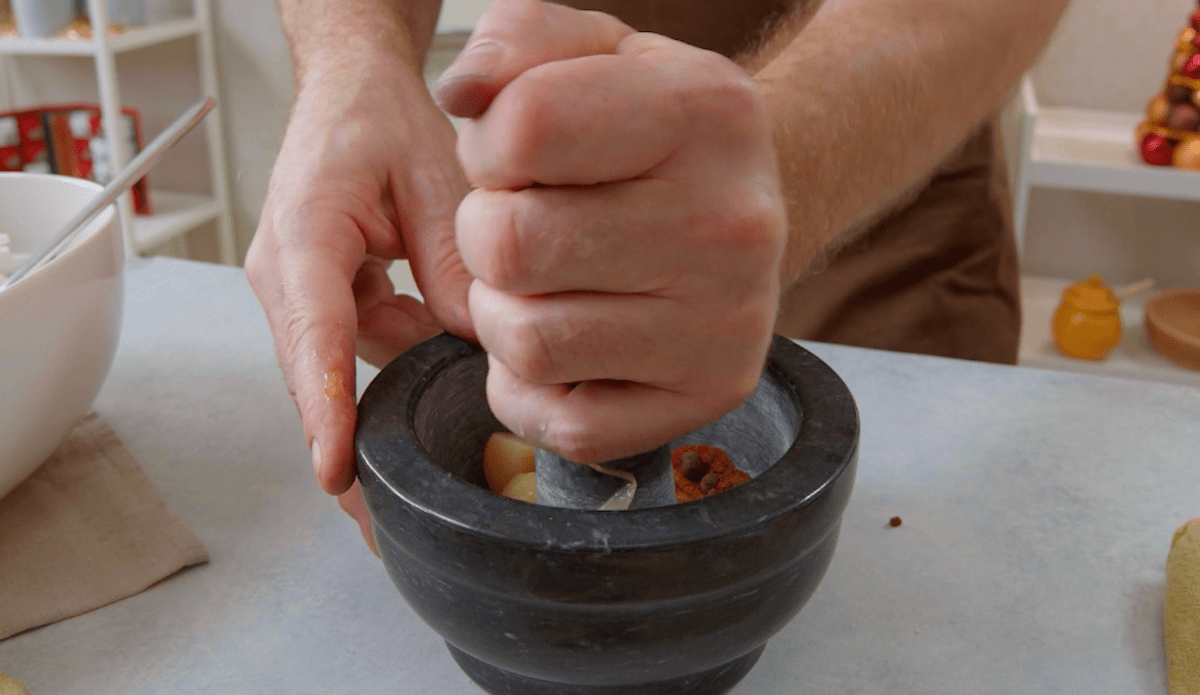 Mehrere GewÃ¼rze und Knoblauch werden in einem MÃ¶rser zu einer Paste verarbeitet