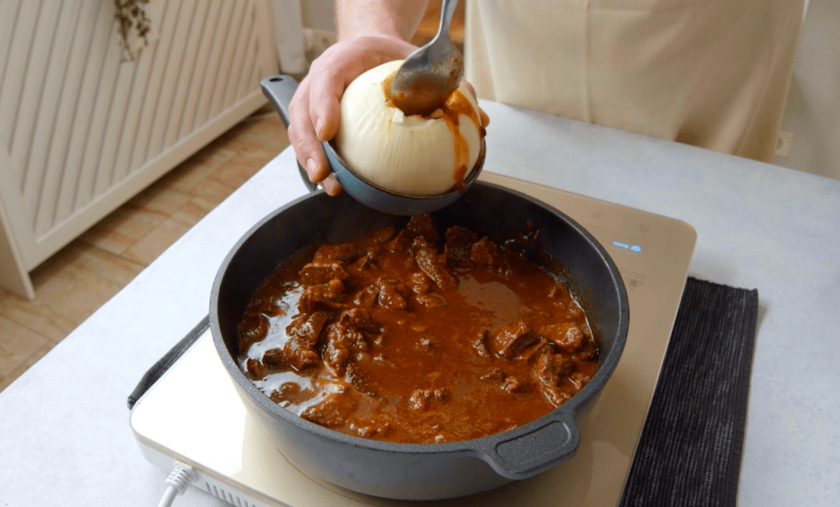 Eine augehÃ¶hlte Zwiebel wird mit Rinderragout gefÃ¼llt