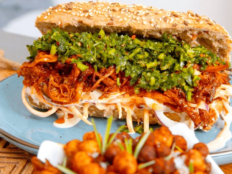 Kräuterseitlinge im Baguettebrötchen mit Krautsalat und Gremolata auf einem Teller.