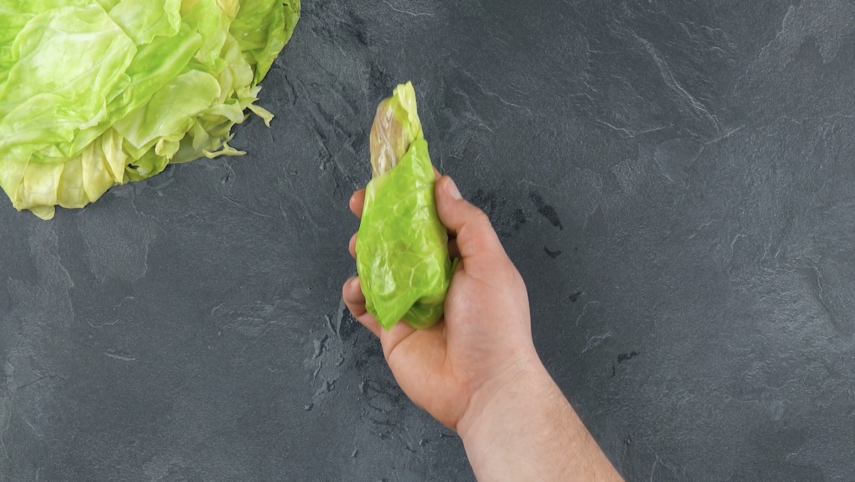 Hackfleisch wird in einem Spitzkohlblatt eingerollt 