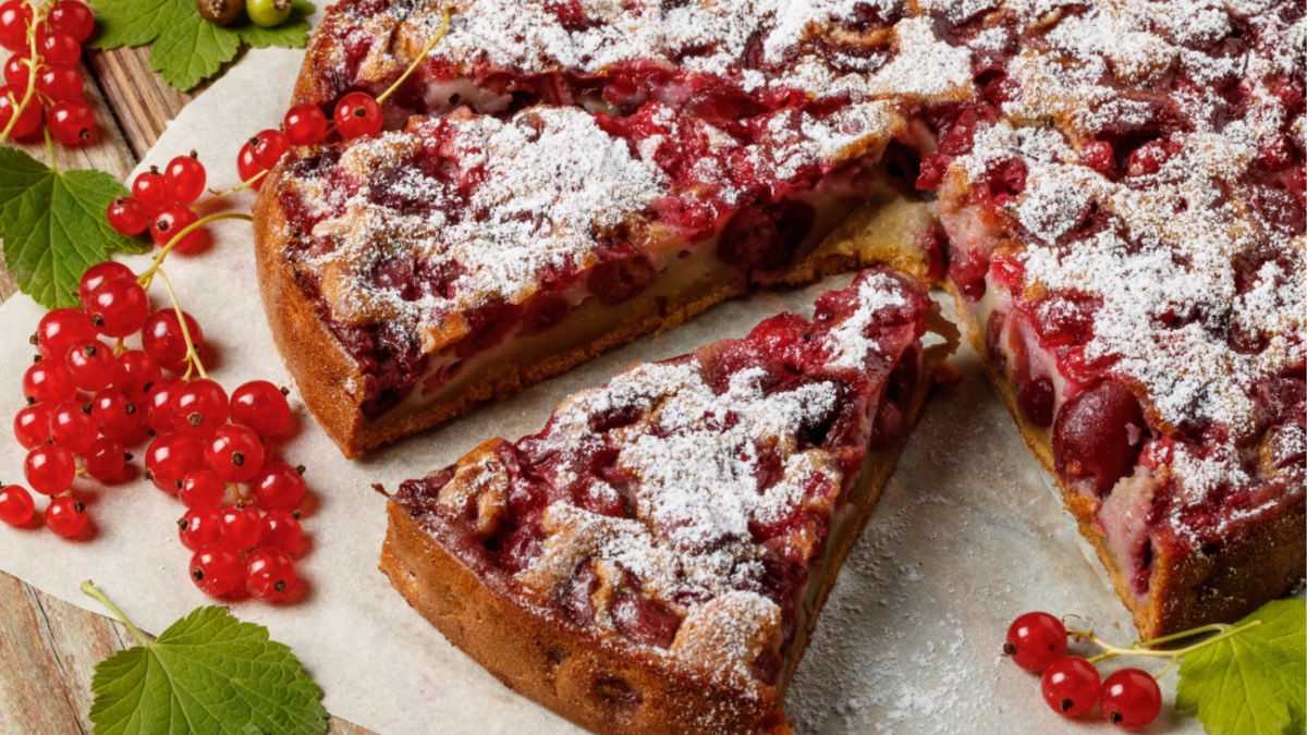 Kuchenplatte mit angeschnittenem Kuchen mit Beeren