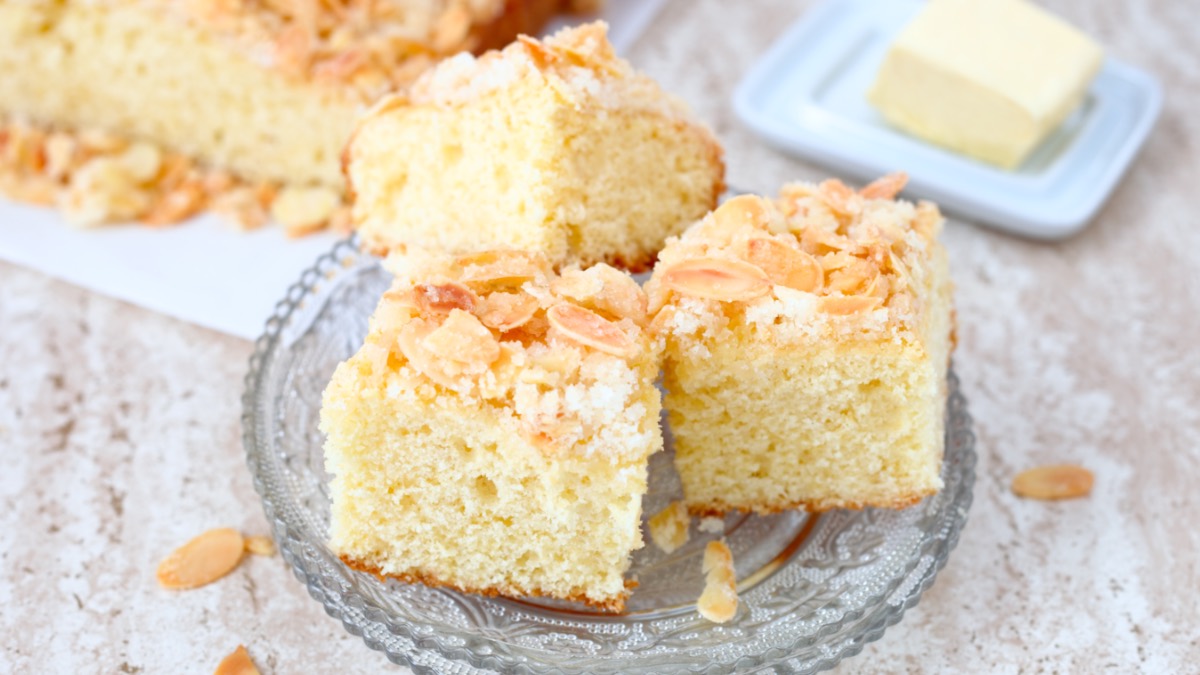 Mehrere Stücke Butterkuchen mit Mandeln auf einem Glasteller.