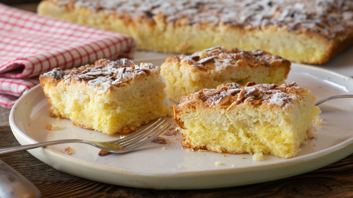 3 Stücke Butterkuchen ohne Hefe auf einem Teller, im Hintergrund das Belch mit dem Kuchen und ein Geschirrtuch.