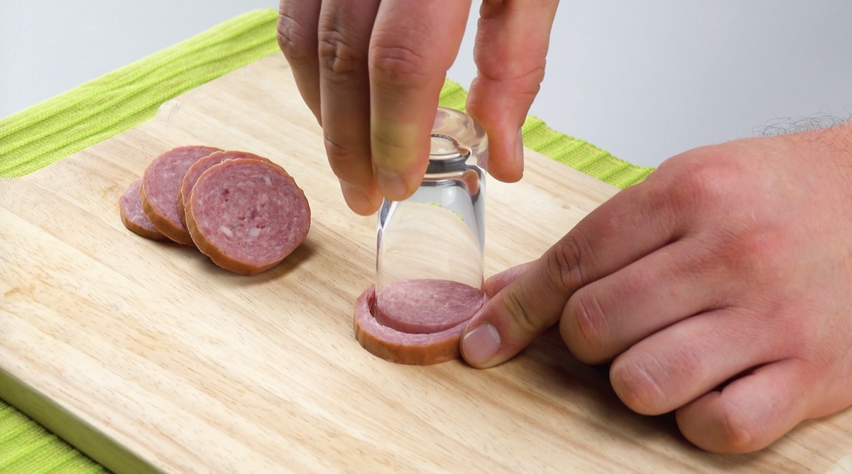 Eine Wurstscheibe wird mit einem kleinen Glas so ausgestochen, das eine Halbmondsichel entsteht