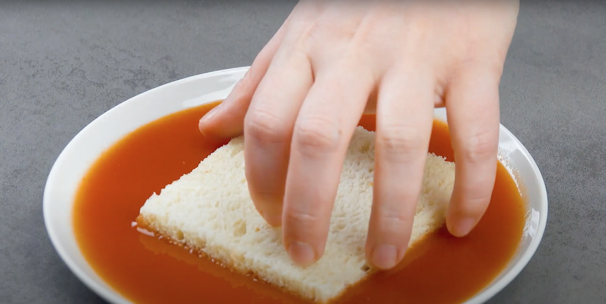 Eine Scheibe Toastbrot ohne Rand wird in Chilisauce gewÃ¤lzt