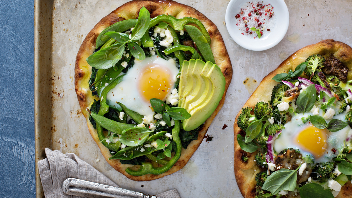 Zwei Frühstückspizzen auf einem Blech mit Backpapier.