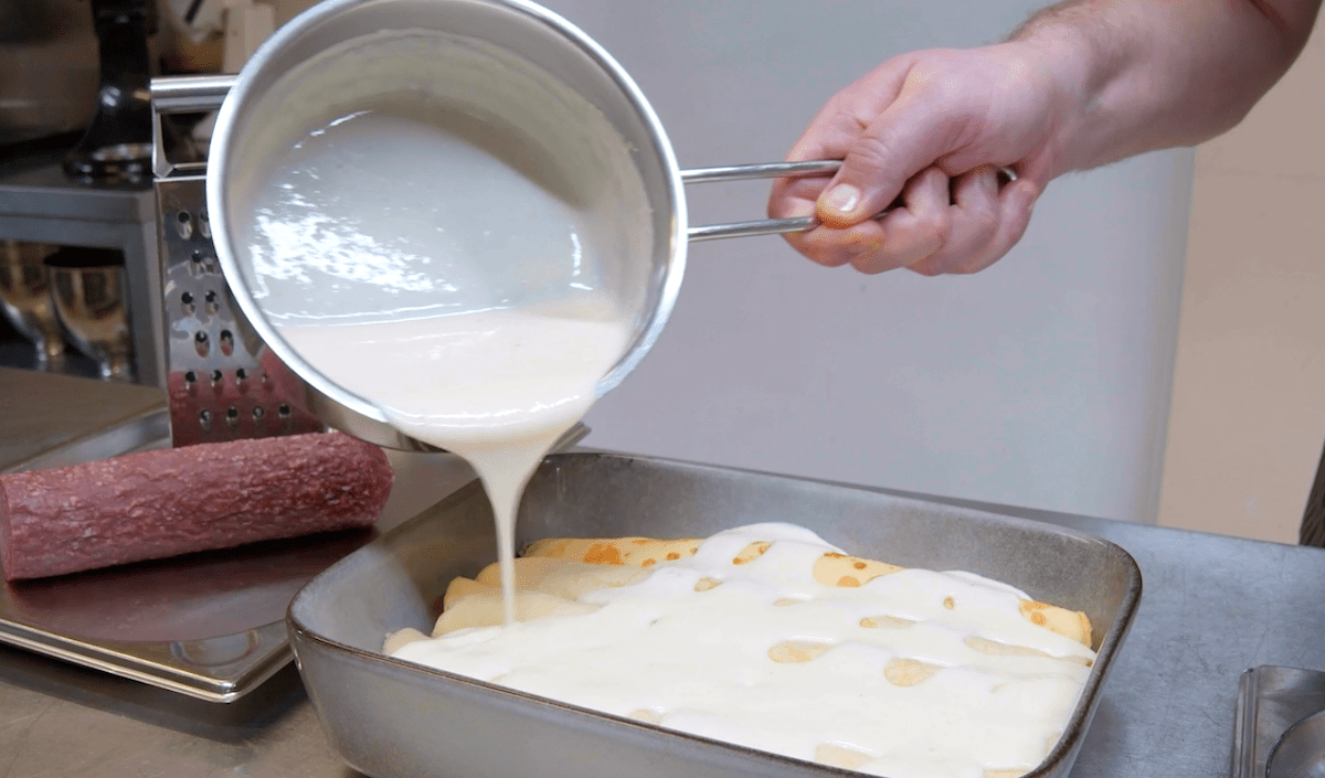 BÃ©chamelsauce wird Ã¼ber die gefÃ¼llten CrÃªpes gegossen