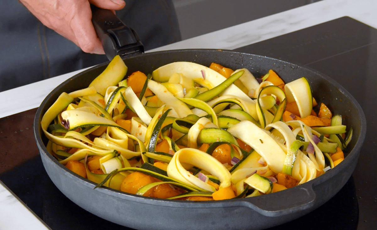 Kartoffeln, Zwiebeln und Zoodles werden in einer Pfanne angebraten