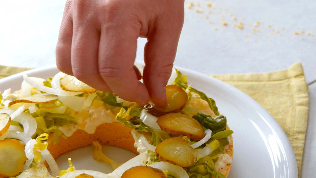 In Scheiben geschnittene GewÃ¼rzgurken werden auf ein Burger Bun gelegt