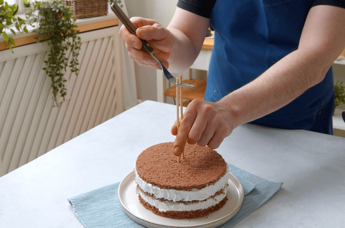 Eine Gabel wird oben an zwei HolzstÃ¤ben fixiert, die in der Schokoladentorte stecken.