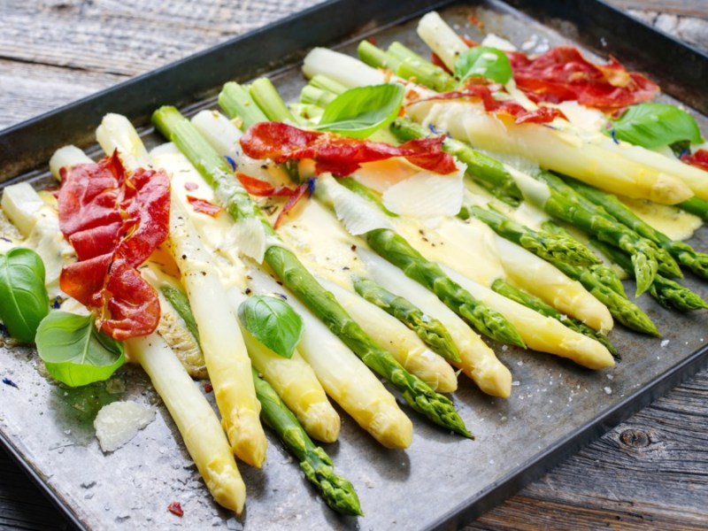 Weißer und grüner Spargel aus dem Ofen auf ein Blech mit Schinken und Sauce hollandaise.