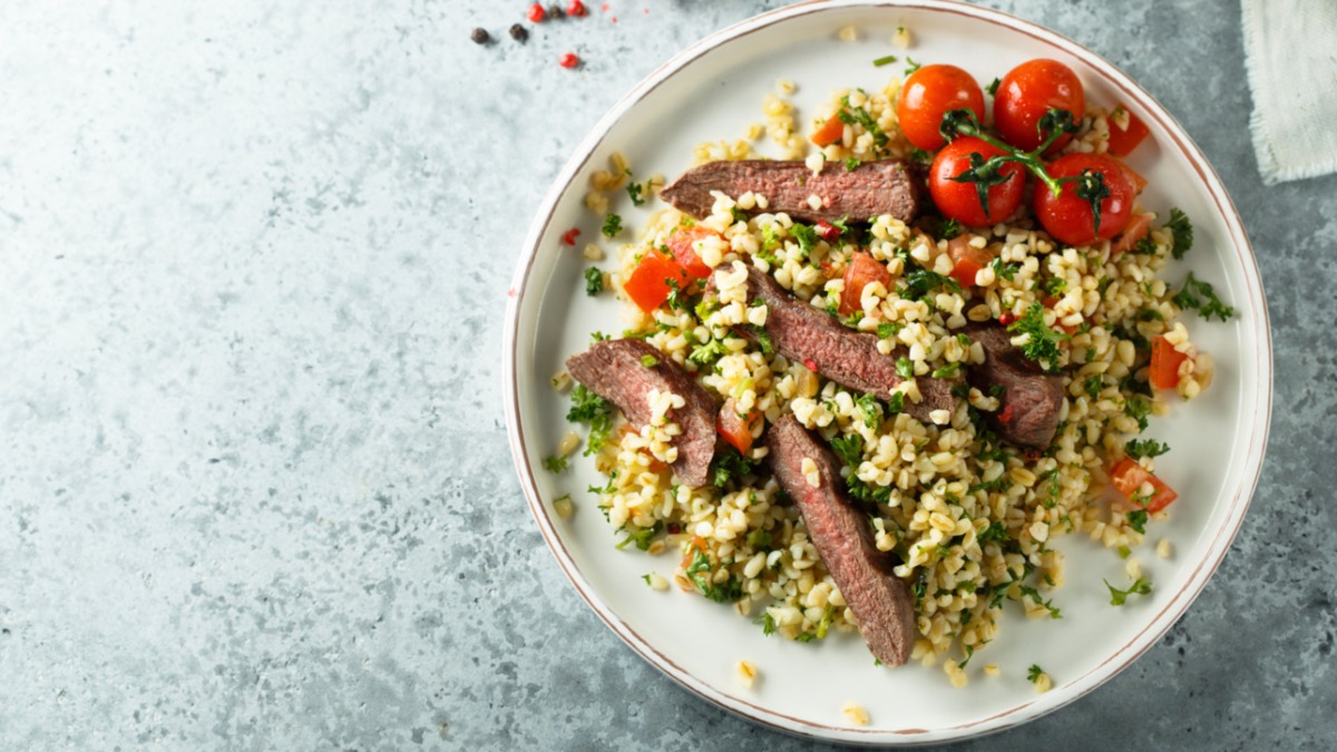 Bulgursalat mit Roastbeef, KrÃ¤utern und frischem GemÃ¼se auf Teller