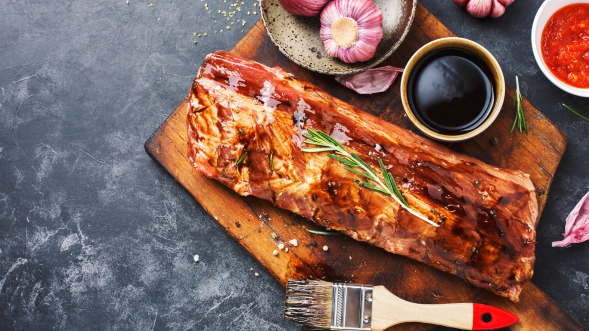 Schweinerippen mit Marinade und GewÃ¼rzen auf einem Holzbrett