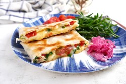 2 getoastete Wraps mit Avocado und Tomaten auf einem blau-weiß gemusterten Teller, darauf auch eingelegtes Gemüse.