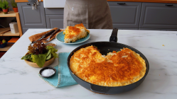 Eine herbstliche Börek-Pfanne mit Kürbis und Yufka-Teig auf einer Küchentheke, daneben eine Schale Salz und ein Teller mit einem Stück des Auflaufes.