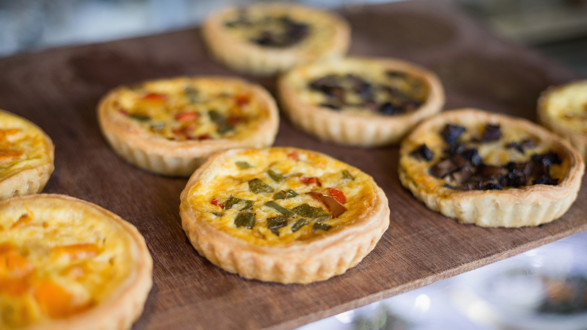 Mini Quiche Variationen auf einem Holzbrett angerichtet