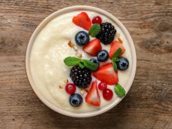 Dinkel-Grießbrei in einer Schüssel, garniert mit Beeren, Minze und Nüssen.