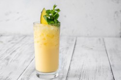 Ein Glas Alkoholfreier Mango-Cocktail mit Eis, garniert mit Minze und einer Mangospalte.