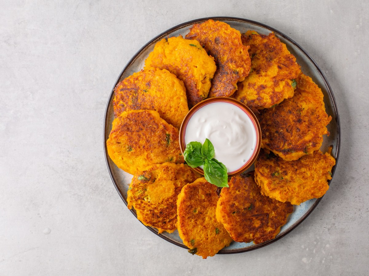 Ein Teller Hash Browns, fächerartig im Kreis angeordnet, in der Mitte eine Schale weißer Dip.