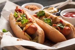 2 Hot Dogs mit selbst gemachter Hot-Dog-Soße und Kräutern und Röstzwiebeln, Nahaufnahme.