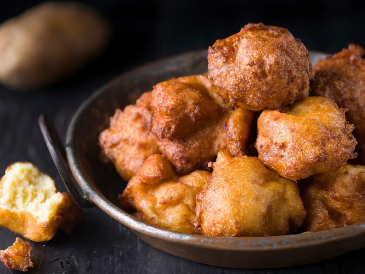 Frittierte Kartoffelkrapfen in einer kleinen Kupferpfanne auf dunklem Untergrund