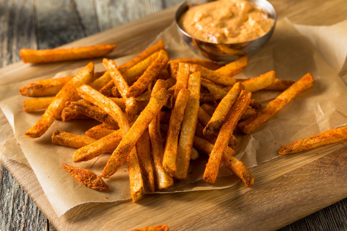 Masala-Fritten auf einem holzbrett mit Limetten-Mayo