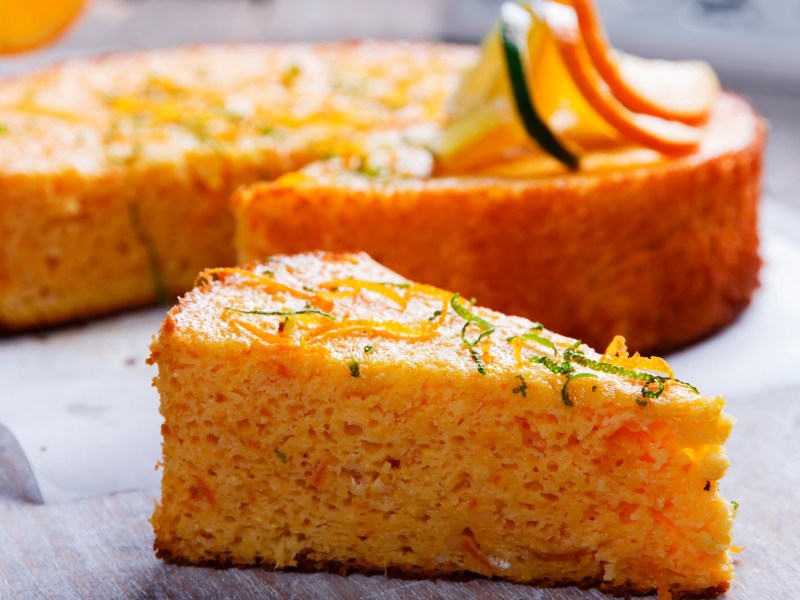 Ein Stück saftiger Orangen-Mandel-Kuchen mit Zeste bestreut.