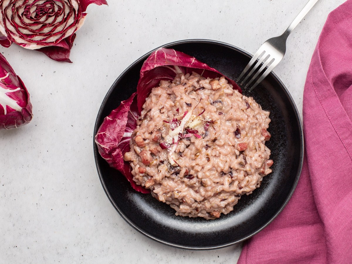 Radicchio-Risotto mit Pancetta auf einem schwarzen Teller