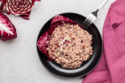 Radicchio-Risotto mit Pancetta auf einem schwarzen Teller