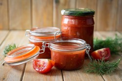 drei Gläser selbstgemachter Ketchup mit Tomaten und Dill garniert.