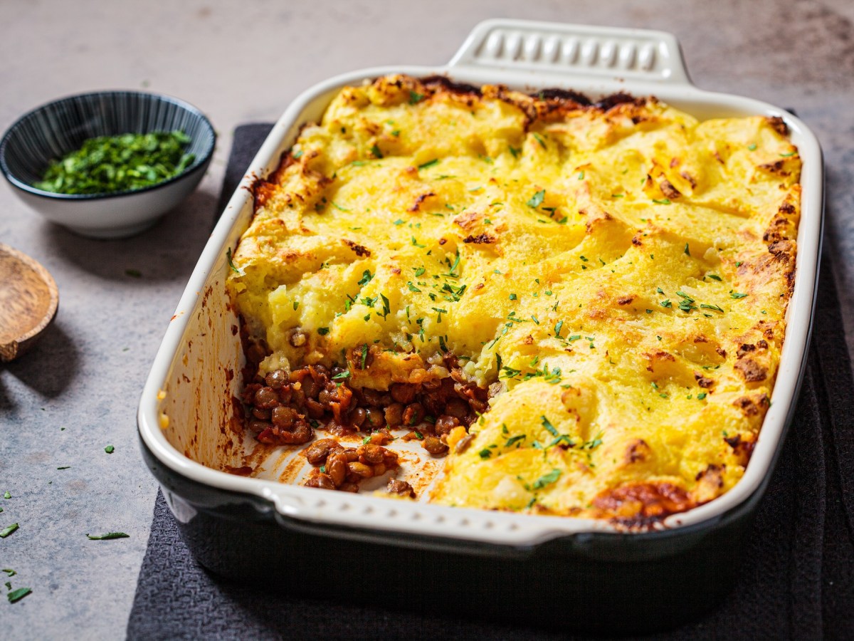 Shepherd's Pie mit Hack und Kartoffelbrei in einer Auflaufform mit Petersilie bestreut, ein Stück ist schon weg