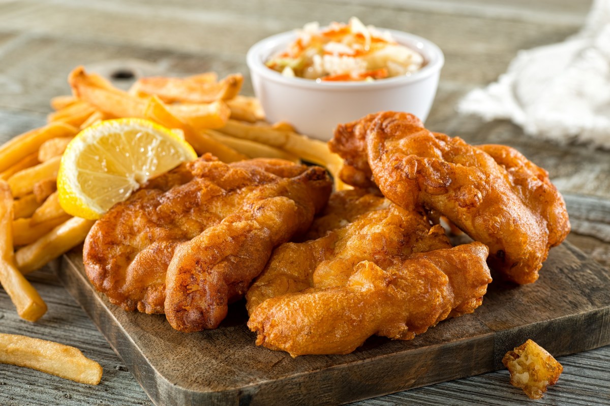 Panieren ohne Ei: frittiertes Essen, das mit veganer Panade zubereitet wurde, daneben Pommes und eine Schale mit Dip.