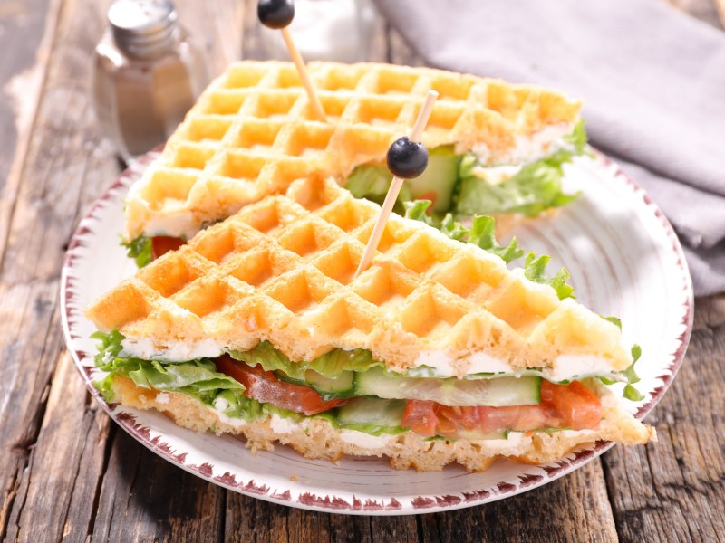 Ein halbiertes Waffel-Sandwich mit Gemüse auf einem Teller.