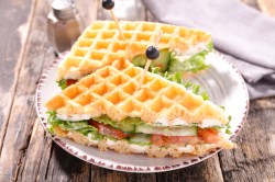 Ein halbiertes Waffel-Sandwich mit Gemüse auf einem Teller.