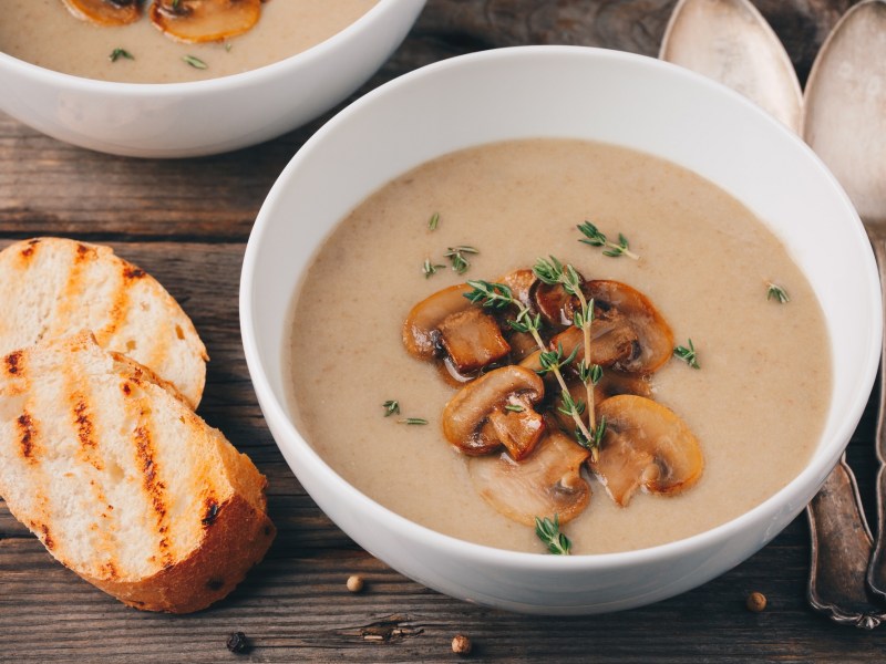 Weiße-Bohnen-Champignon-Suppe in einer weißen Schüssel mit gerösteten Brot und Thymian garniert