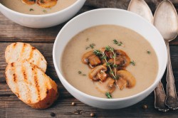 Weiße-Bohnen-Champignon-Suppe in einer weißen Schüssel mit gerösteten Brot und Thymian garniert