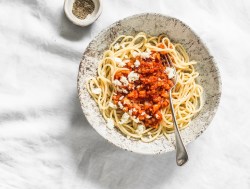 Teller mit Blumenkohl-Bolognese auf hellem Tischtuch.