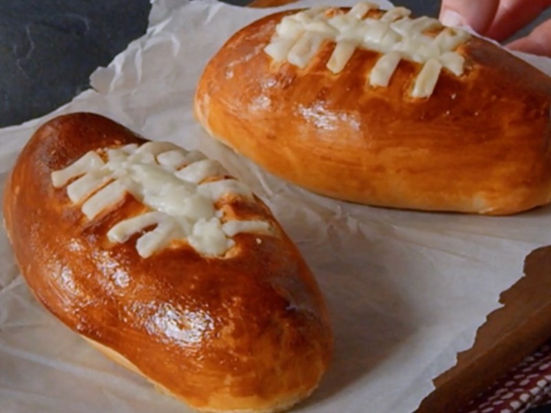 Zwei Football-Snacks mit Käsefüllung auf Backpapier.