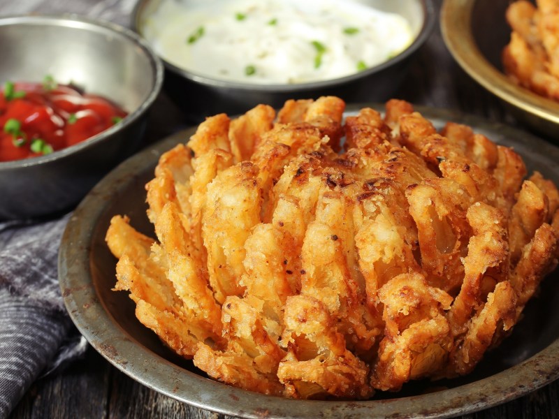 Frittierte Zwiebelblume in einer braunen Schale, serviert mit Dips.