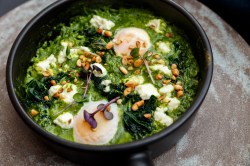 Pfanne mit grünem Shakshuka, Pinienkernen und pochierten Eiern